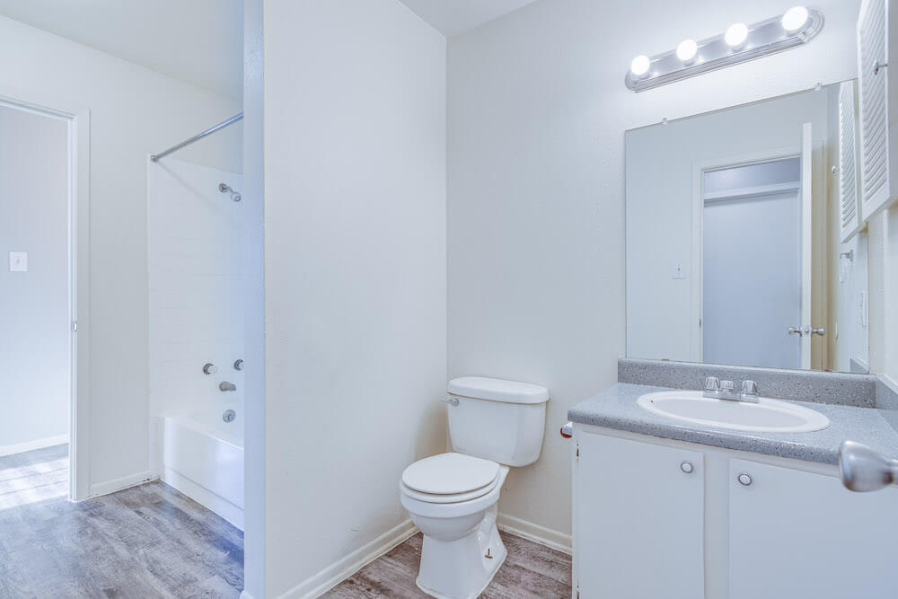 A well-lit bathroom with white cabinets.