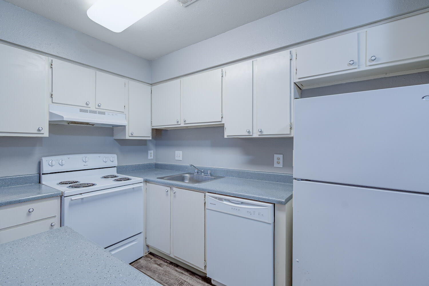 A kitchen with white cabinets and appliances.